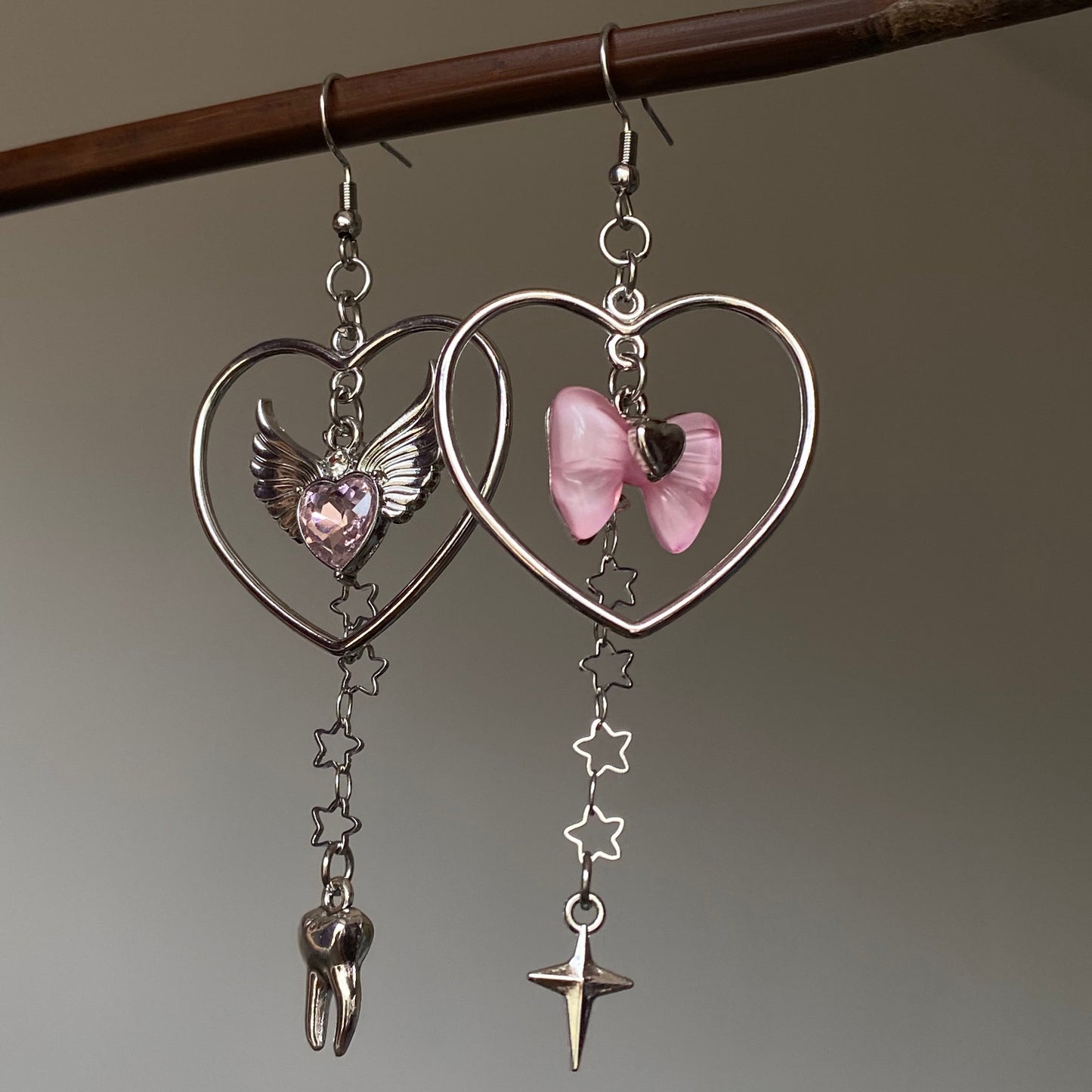 Asymmetrical heart charm earrings with silver-tone open heart frame and pink bow charm
