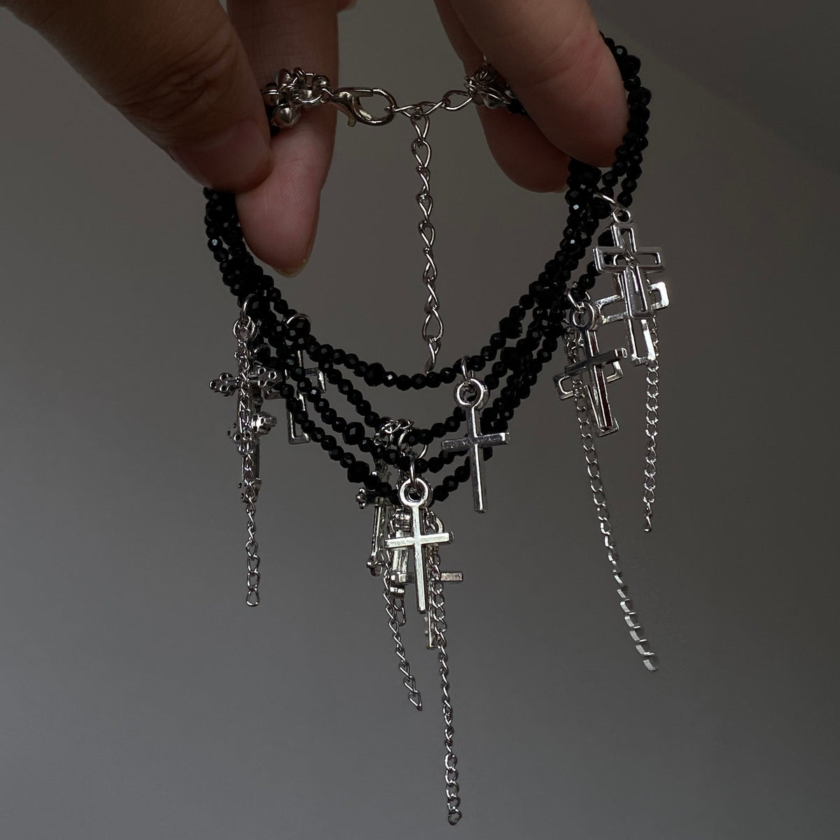 Black crystal cross tassel bracelet with layered bead strands and silver-tone charms