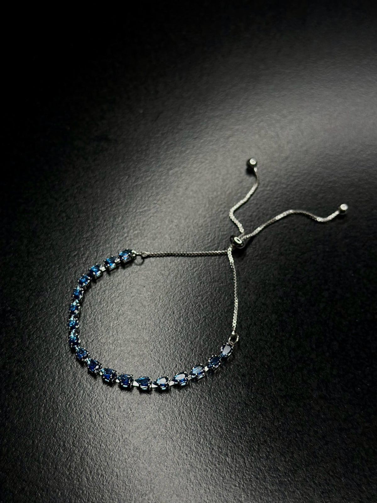 Silver-tone blue bracelet with linked deep blue oval gemstones and slim chain