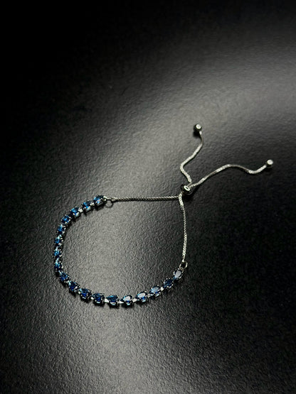 Silver-tone blue bracelet with linked deep blue oval gemstones and slim chain