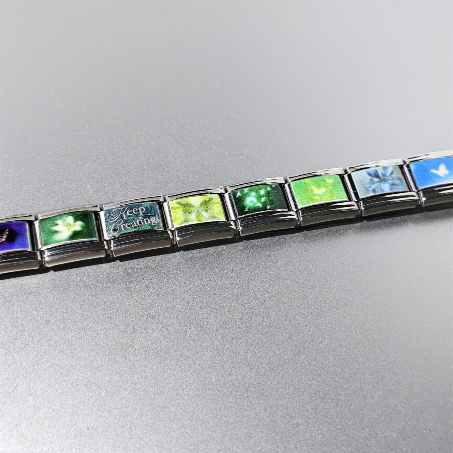 Blue and green butterfly charm links arranged in a stainless steel bracelet