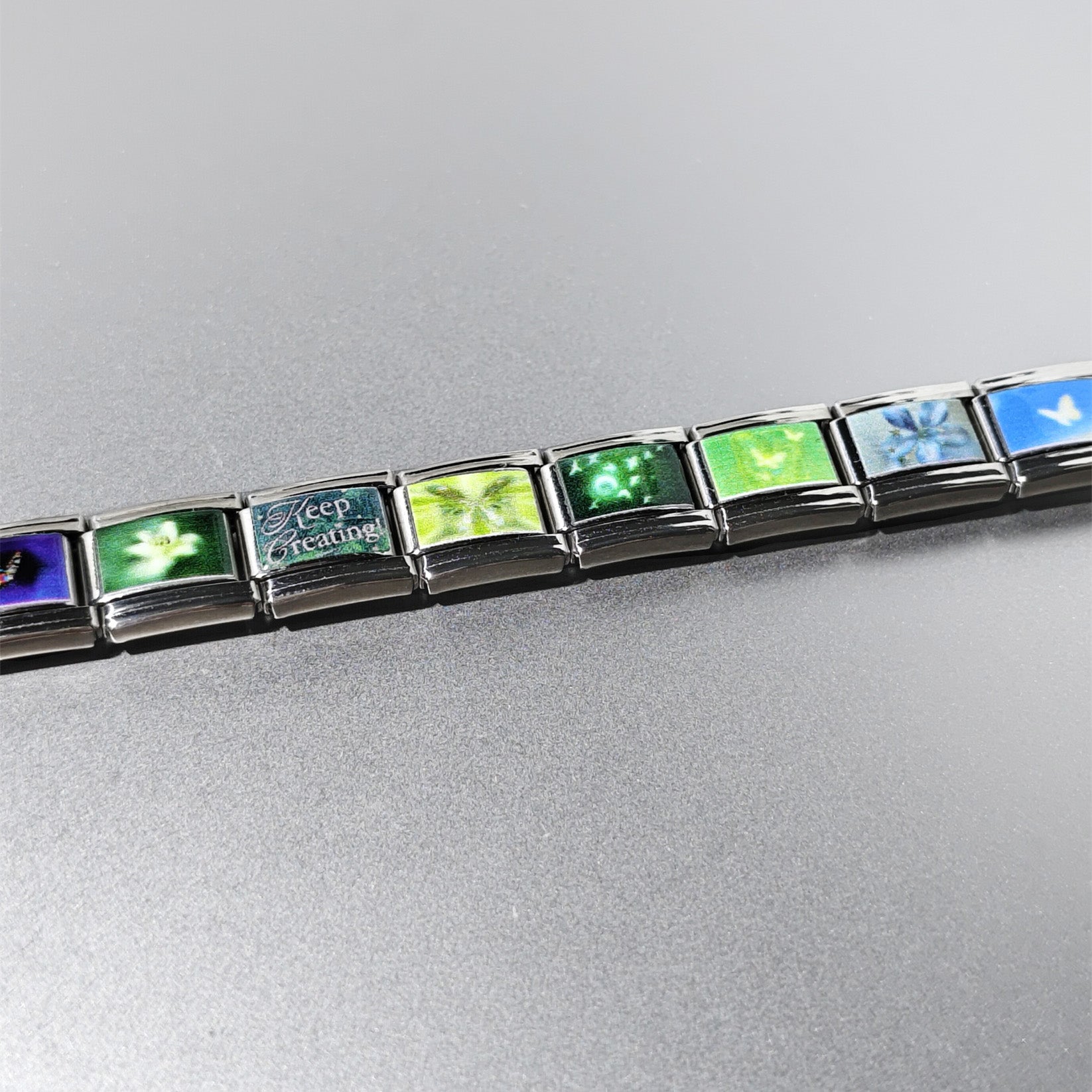 Blue and green butterfly charm links arranged in a stainless steel bracelet
