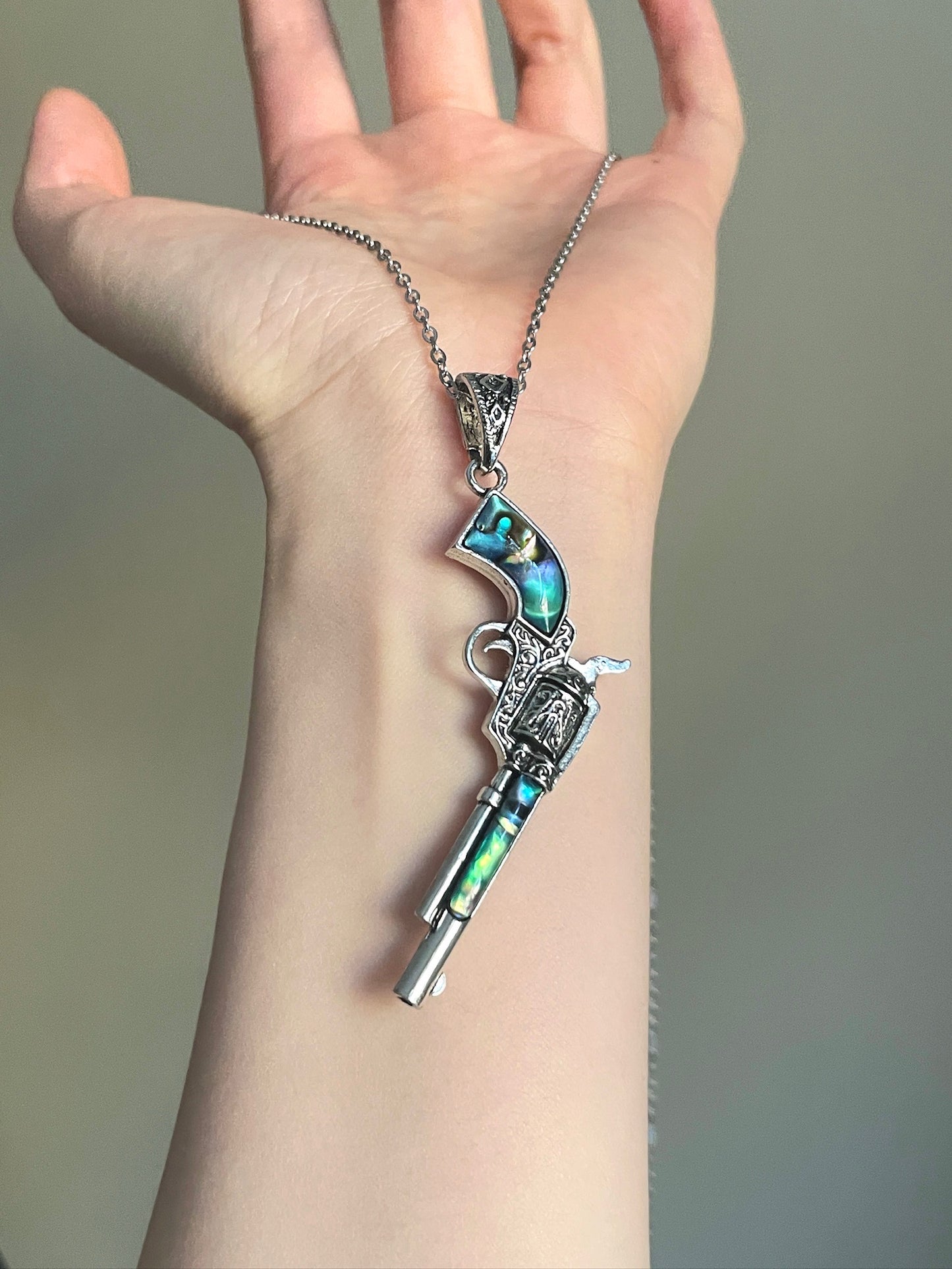 Vintage revolver necklace with ornate metalwork and shifting shell inlay panels