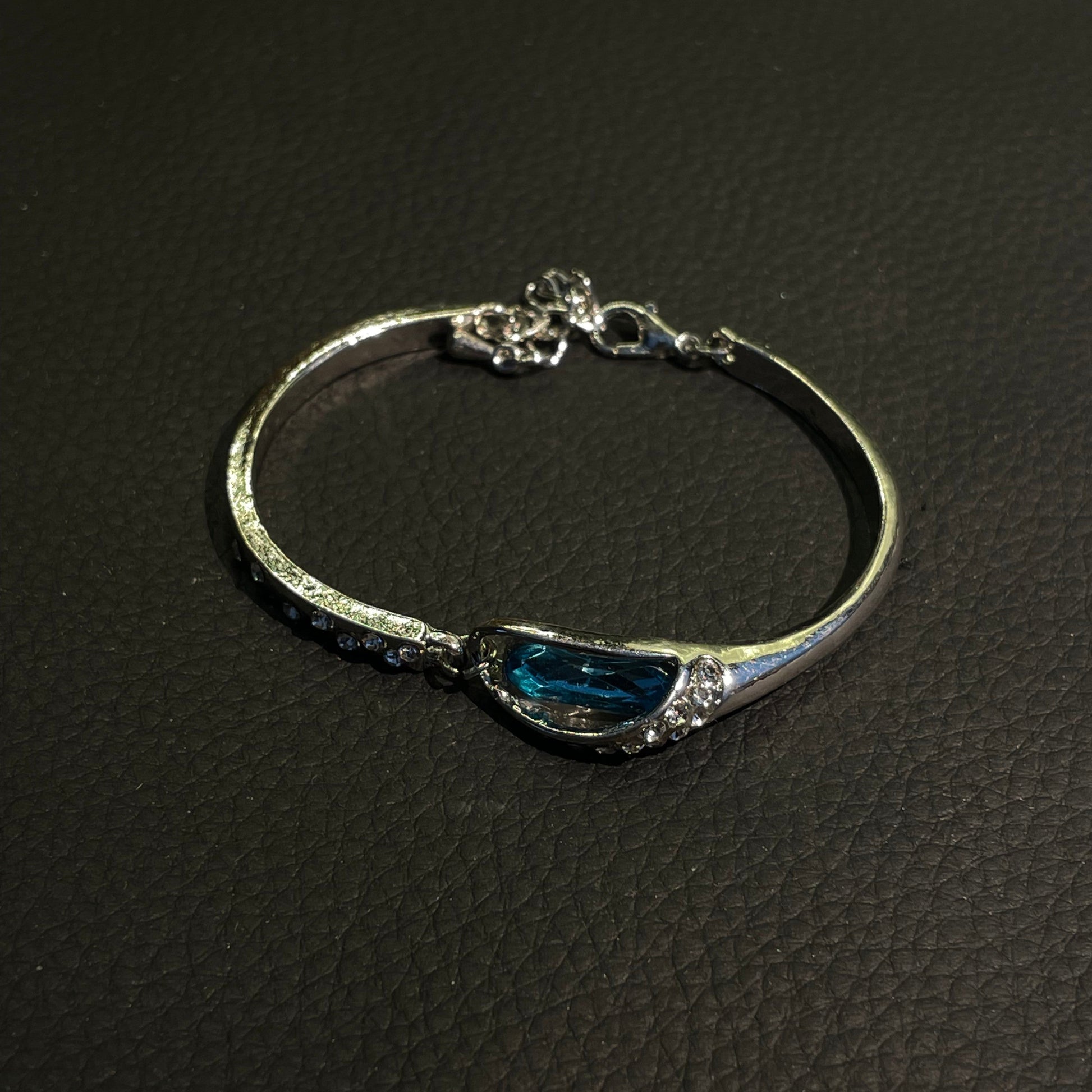 Blue teardrop crystal bangle with silver-tone curved frame and sparkling accents