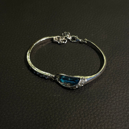 Blue teardrop crystal bangle with silver-tone curved frame and sparkling accents