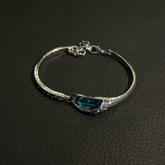 Blue teardrop crystal bangle with silver-tone curved frame and sparkling accents
