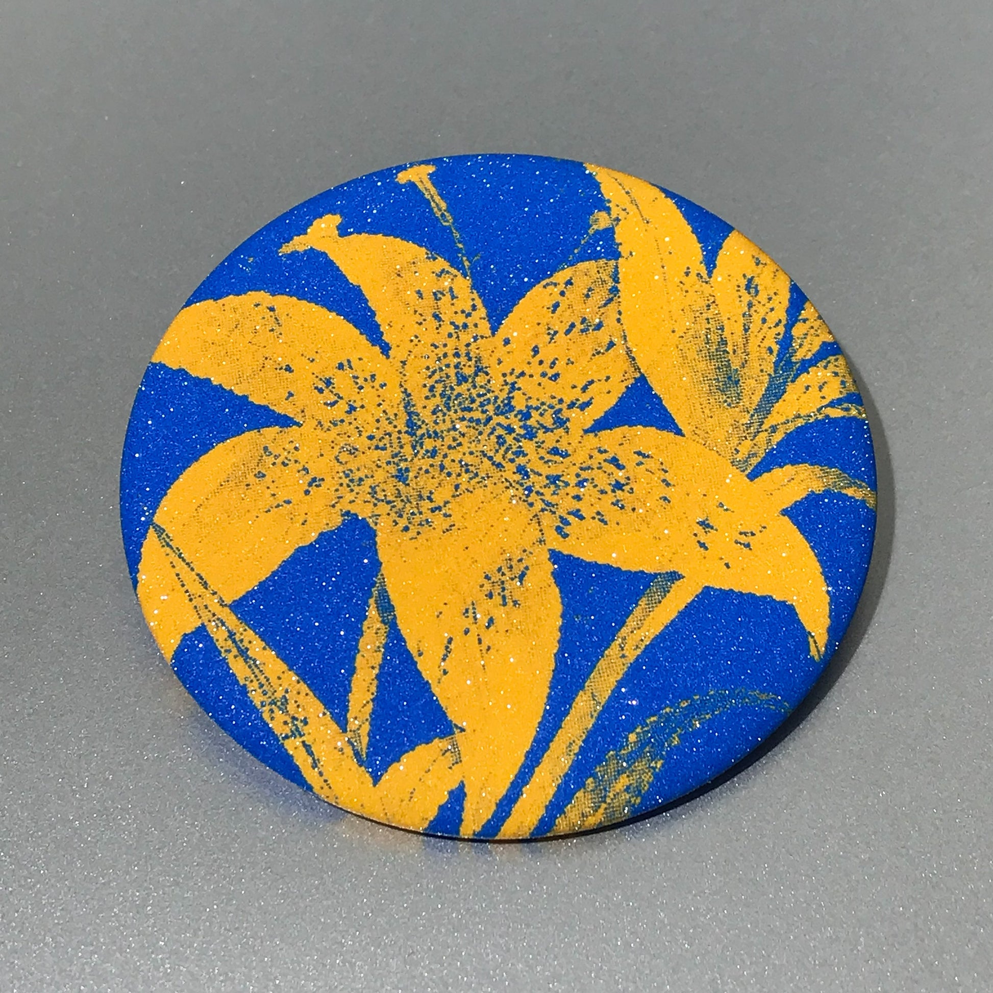 Round pocket mirror with electric blue and yellow high-contrast artwork