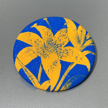 Round pocket mirror with electric blue and yellow high-contrast artwork