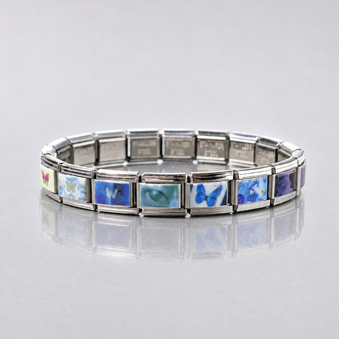 Full view of a silver-tone modular butterfly bracelet on a reflective surface