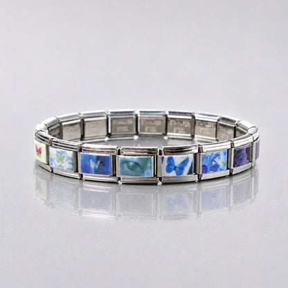 Full view of a silver-tone modular butterfly bracelet on a reflective surface