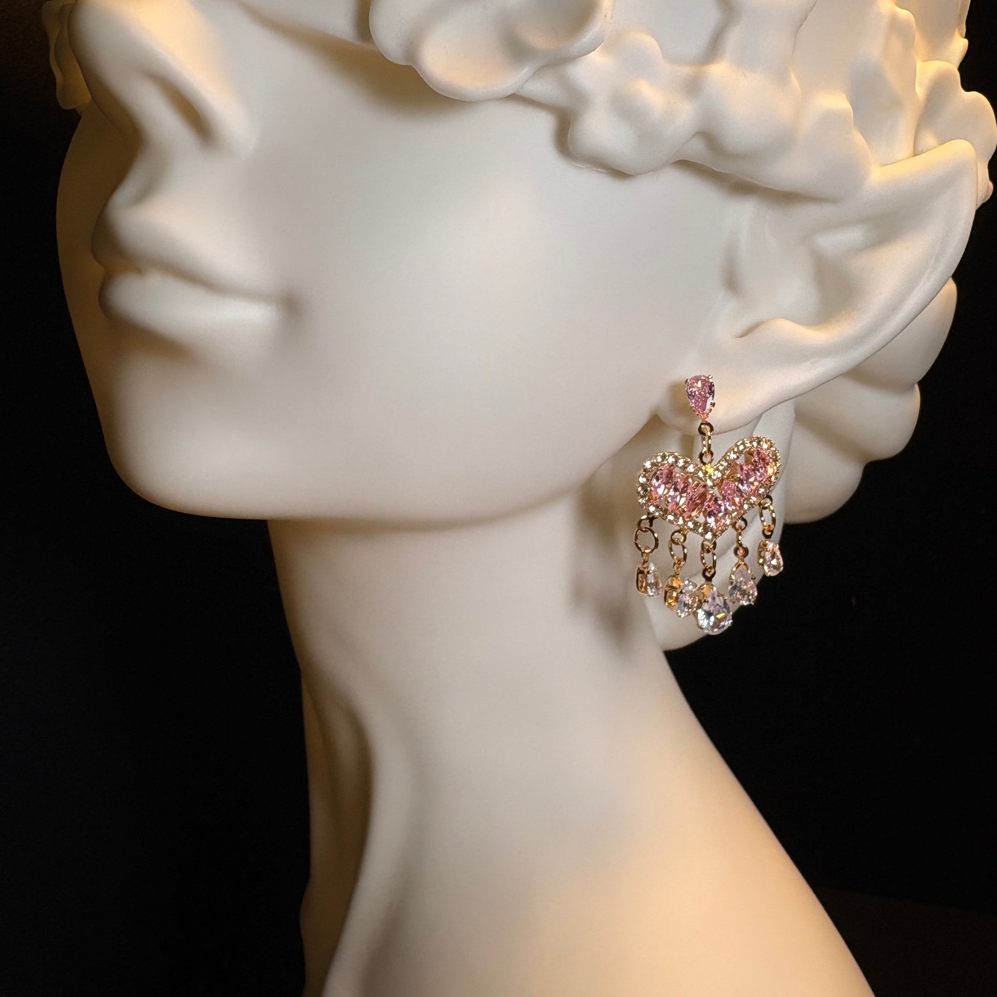 Close-up of pink zircon heart dangle earrings with gold-tone details