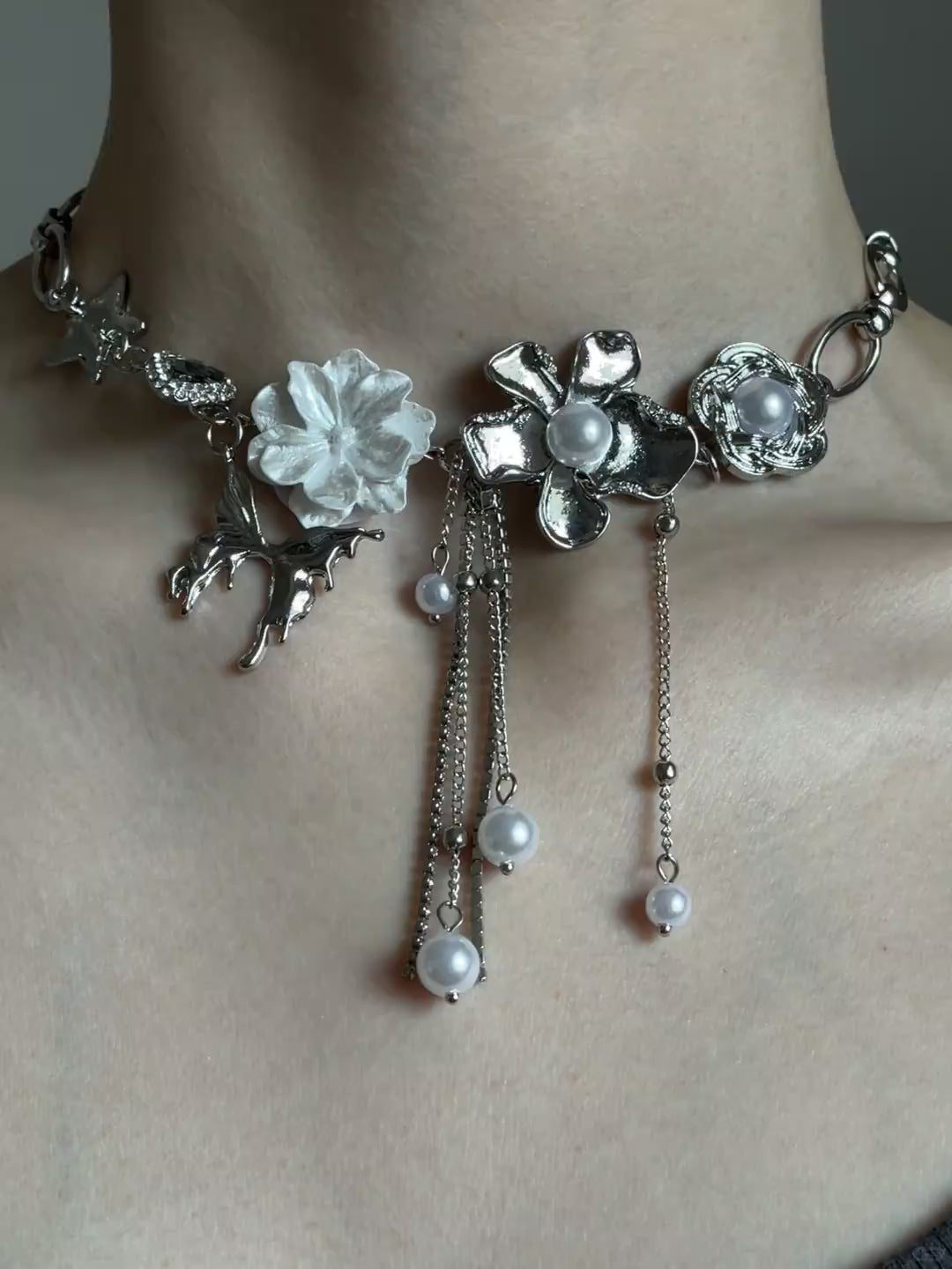 Close-up of silver-tone statement choker with pearl-style drops and chain tassels