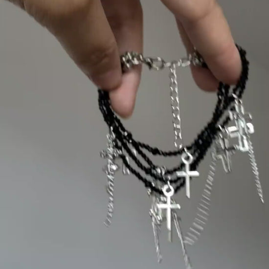 Silver cross tassel bracelet with black crystal-style beads and dark styling mood