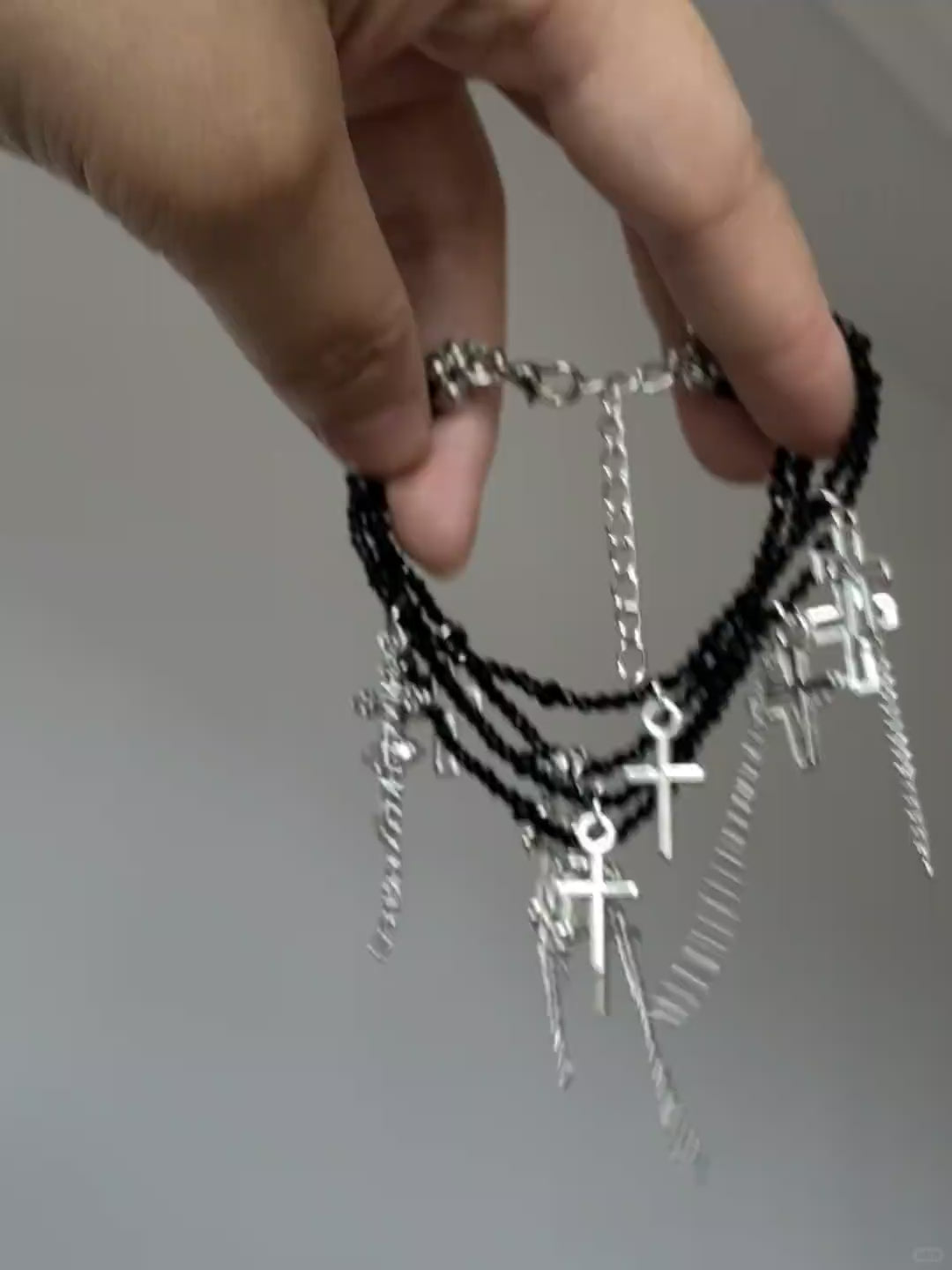Silver cross tassel bracelet with black crystal-style beads and dark styling mood