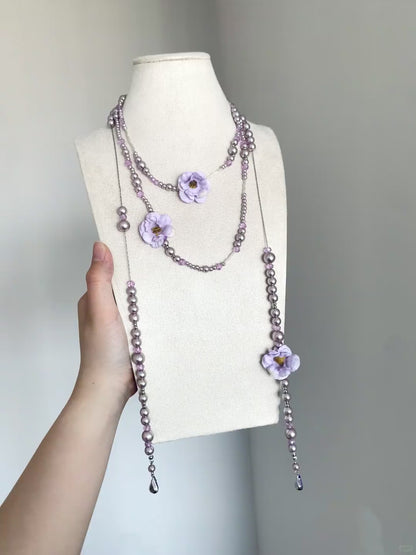 Purple pearl-style necklace with flower charms and soft romantic styling