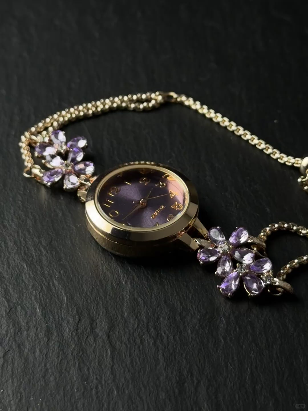 Adjustable watch bracelet with purple face, flower accents, and small crystal end charm