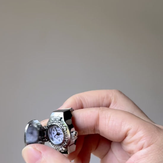 Chunky watch ring worn on fingers with silver-tone frame and palm design