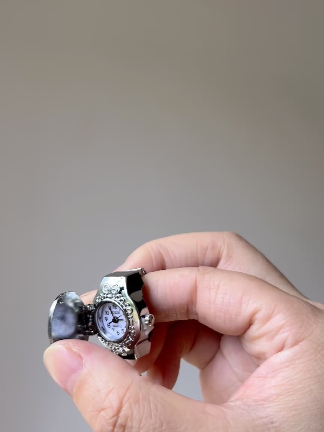 Chunky watch ring worn on fingers with silver-tone frame and palm design