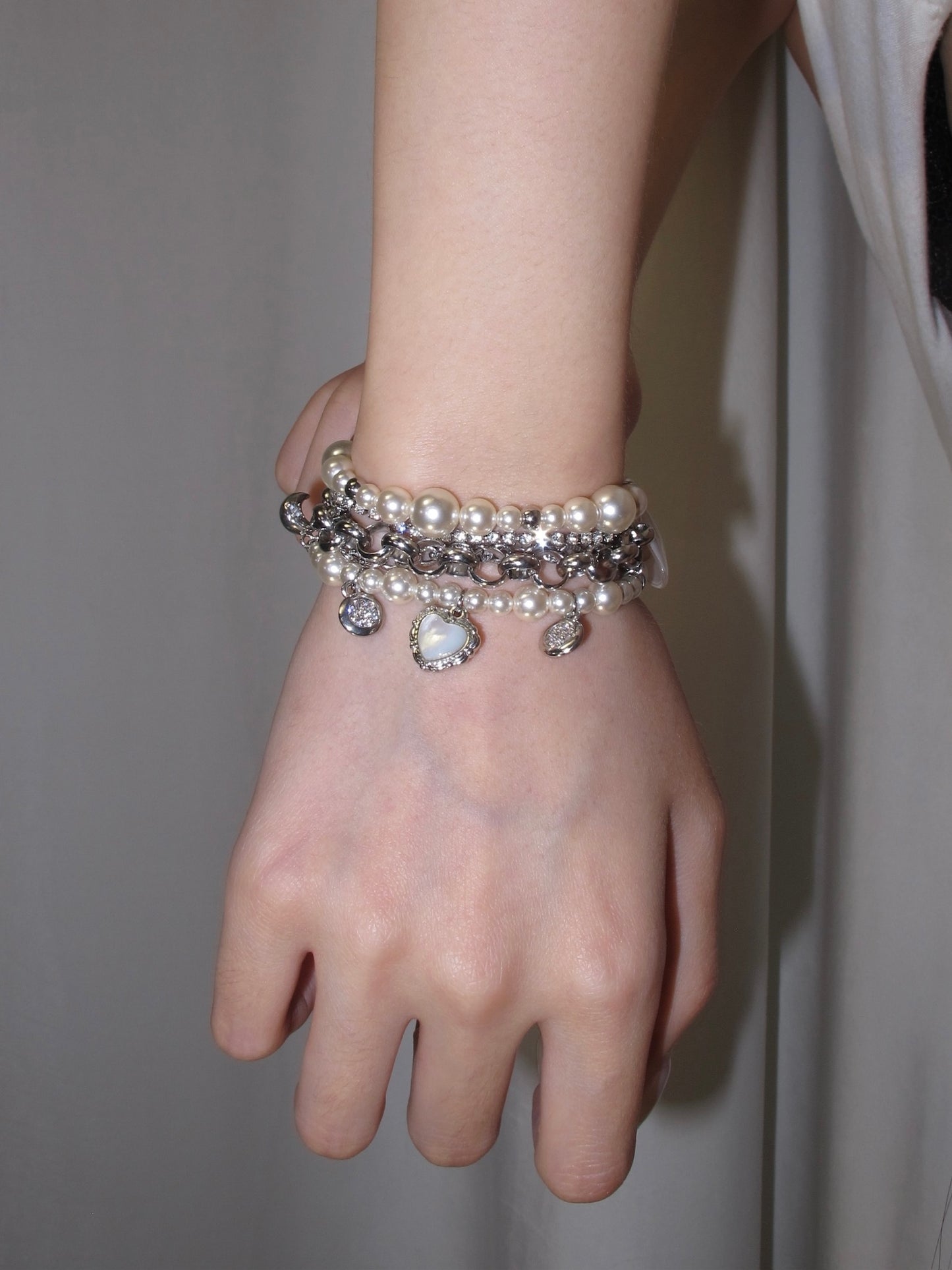 Pearl chain charm bracelet with sweet coquette mood and mixed silver-tone layers